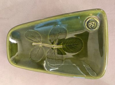 une assiette verte posée sur une table, avec une feuille dedans