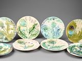 six plates with green and white designs on them on a gray surface