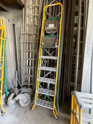 Plusieurs échelles sont empilées les unes sur les autres dans une pièce.