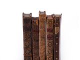 several old books are stacked on top of each other on a white surface