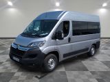 La camionnette argentée est garée dans une grande pièce au sol carrelé en damier.