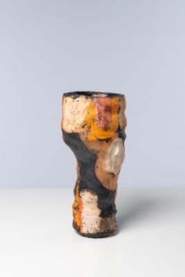 un vase orange et noir posé sur une table blanche