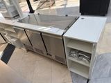 a stainless steel counter with a glass door on it