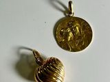 two gold pendants with a coin on a white surface