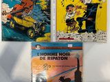 trois bandes dessinées sont exposées sur une surface blanche
