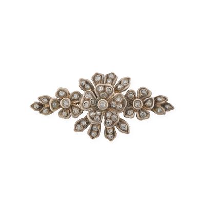 un gros plan d'une broche en forme de fleur sertie de diamants, sur fond blanc