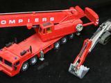 un camion jouet rouge et une grue rouge sur fond noir
