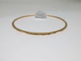 gros plan d'un bracelet en or sur une surface blanche