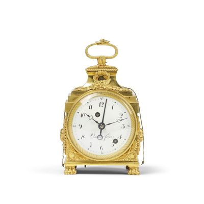 une horloge en or posée sur une surface blanche