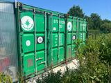 a green shipping container sitting in the middle of a field