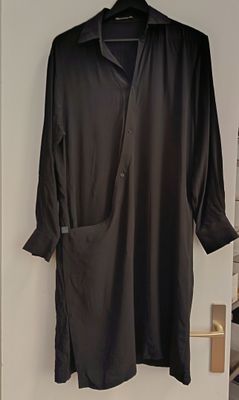 black shirt hanging on a hanger in a white room