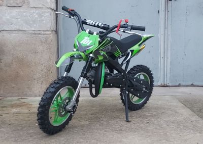 a small green dirt bike parked in front of a garage