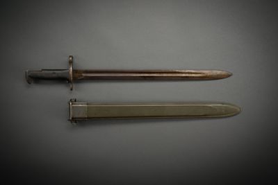 an old dagger and a knife on a gray surface