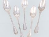 un ensemble de cinq cuillères en argent et de cuillères à soupe posées sur un plateau blanc