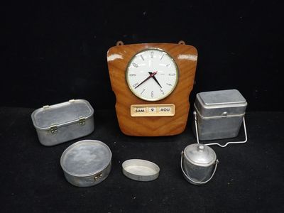une horloge en bois et des boîtes en fer-blanc posées sur une table noire
