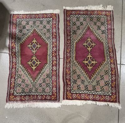 deux tapis posés sur un sol carrelé, avec une plante en pot à l'arrière-plan
