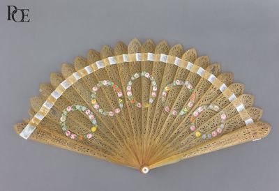 un ventilateur orné de fleurs, posé sur une table