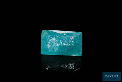 an emerald stone on a black surface with a black background