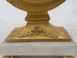 a gold clock with a white face on a stand
