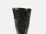 un vase noir posé sur une surface blanche