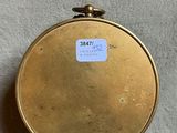 a small gold pocket watch on a white surface