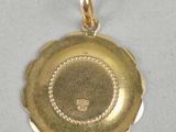 a close up of a gold pendant on a white surface