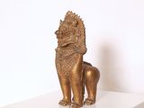 une statue en or représentant un lion, posée sur une étagère blanche