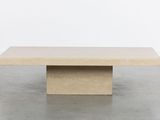 a beige square coffee table with a square base on a concrete floor