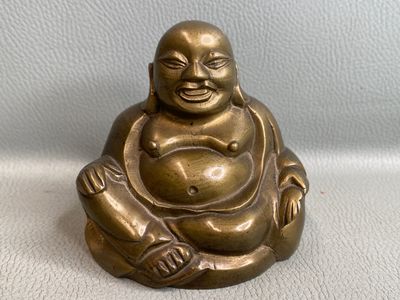 statue d'un Bouddha souriant assis sur une surface blanche