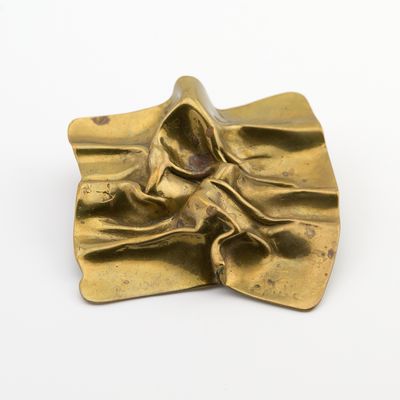 sculpture en laiton représentant une femme assise sur un objet en forme de feuille