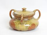 a brown and yellow pot with a lid on a white surface