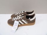 brown and white adidas sneakers with white laces and a price tag