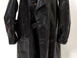 un trench-coat en cuir noir posé sur un mannequin, sur fond blanc