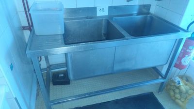 two sinks in the kitchen with a trash can and a trash can