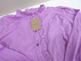 purple shirt with ruffles and a tag on a hanger