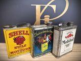 three vintage shell oil cans sitting on top of a wooden table