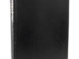 a black book with gold trim sitting on top of a white surface