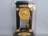 une horloge placée sous un dôme en verre, posée sur une table