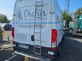 une camionnette garée sur un parking, avec une échelle à l'arrière