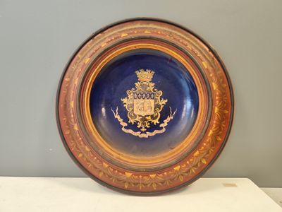 une assiette bleue et dorée sur laquelle figure un blason