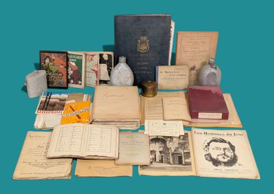 de nombreux livres anciens posés sur une table, à côté d'une bouteille d'eau