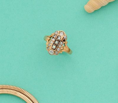 deux bagues et un collier posés sur une surface turquoise, à côté de coquillages