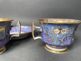 two blue and gold cups and saucers with flowers on them