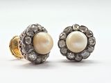 deux paires de boucles d'oreilles en perles et diamants posées sur un fond blanc