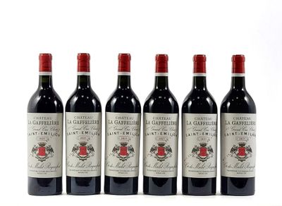 six bottles of red wine are lined up on a white surface