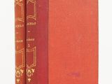 an old book sitting on top of a white table next to a red book