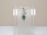 a necklace with a green stone on it in a clear display case