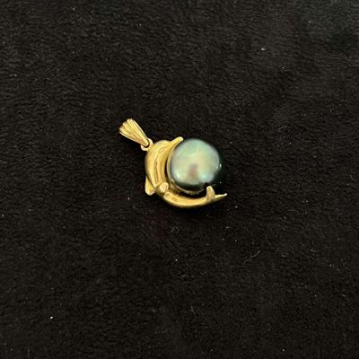un gros plan d'un pendentif en or orné d'une perle