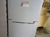 a white refrigerator with a sticker on it in a warehouse