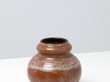 un petit vase marron posé sur une table blanche